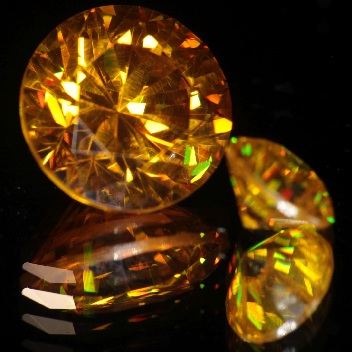Two Bismuth Germanate Gemstones faceted into rounds, one orange, one yellow.