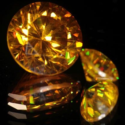 Two Bismuth Germanate Gemstones faceted into rounds, one orange, one yellow.