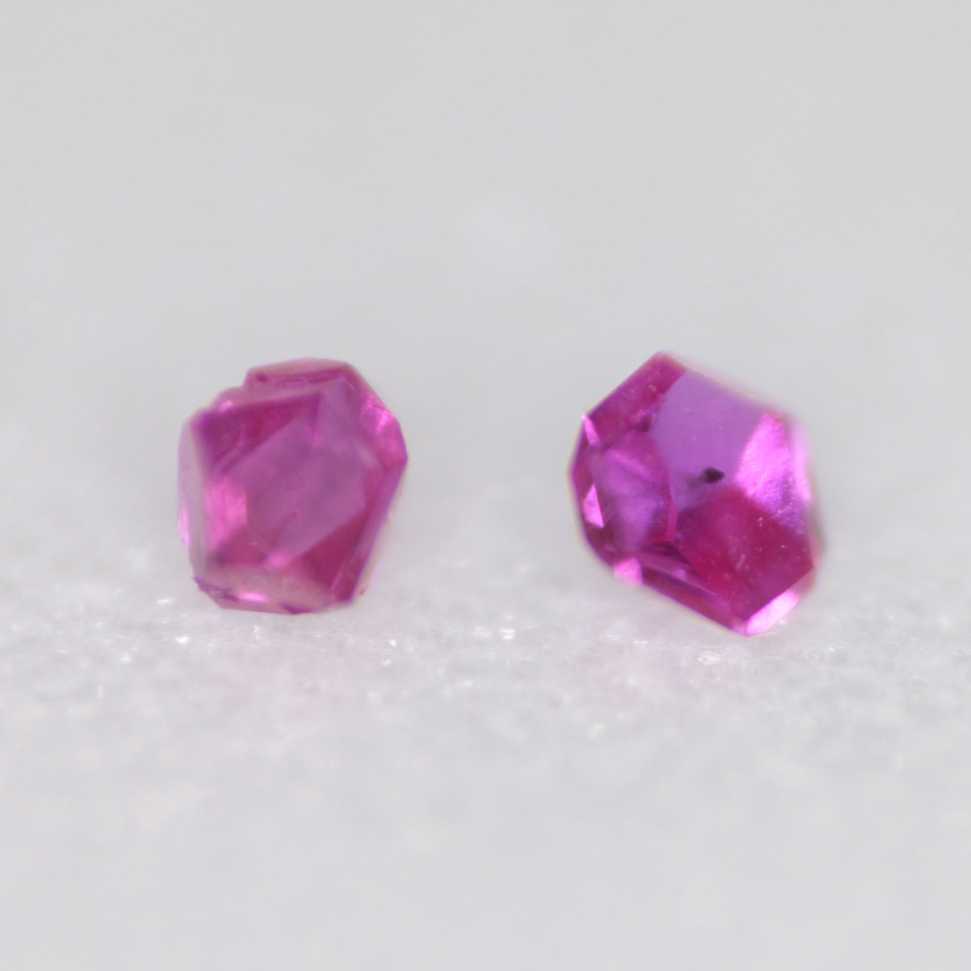 Two flux-grown bright pink synthetic rubies on a white background
