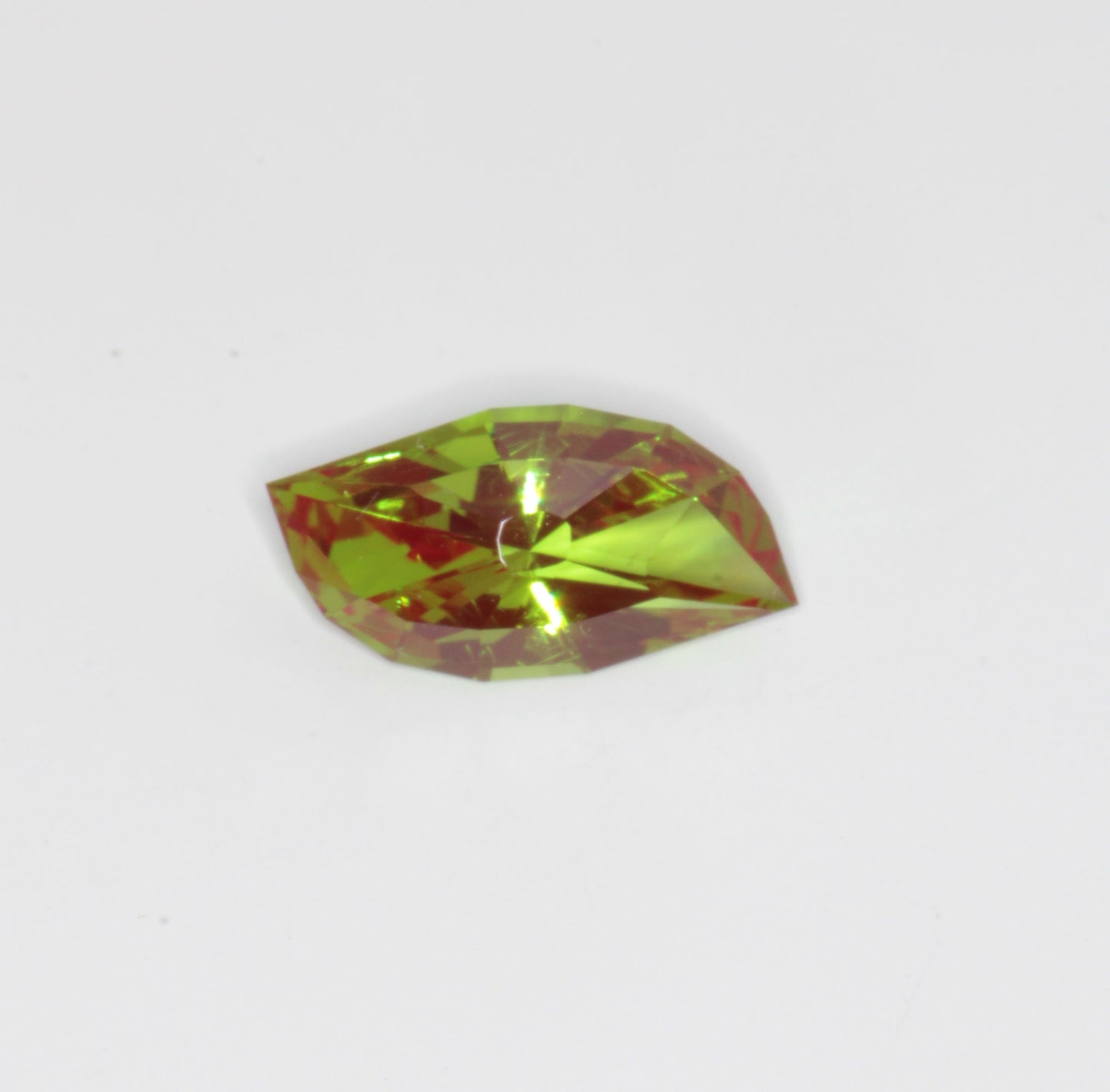 A faceted, red and green, synthetic Christmas garnet gemstone cut in an eye pattern against a white background. Cr:YAG