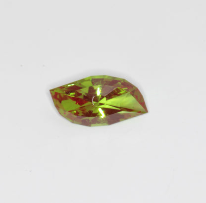 A faceted, red and green, synthetic Christmas garnet gemstone cut in an eye pattern against a white background. Cr:YAG