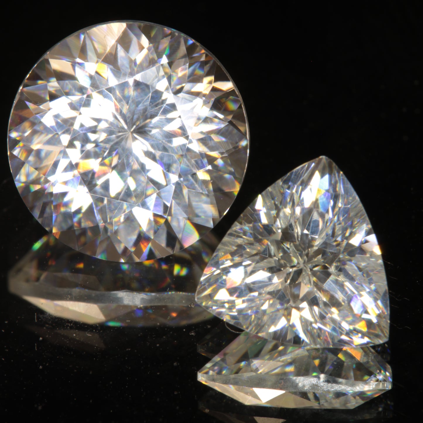 Two Clear White Lithium Tantalate Gemstones on a dark background showing sparkling rainbows