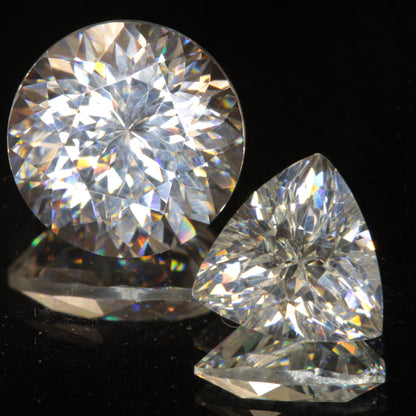 Two Clear White Lithium Tantalate Gemstones on a dark background showing sparkling rainbows