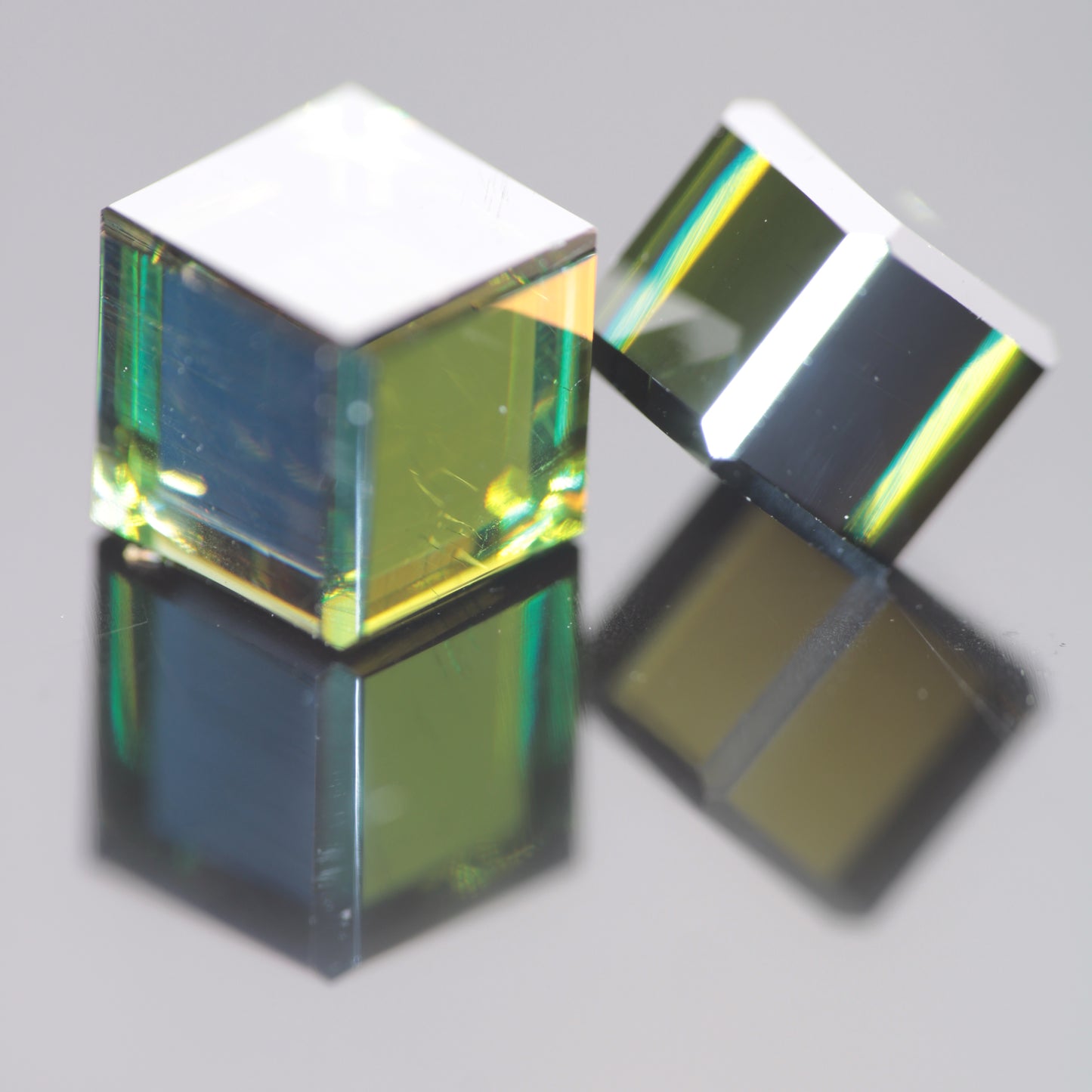 Two cubes of dichroic moissanite, the yellow and blue colors visible