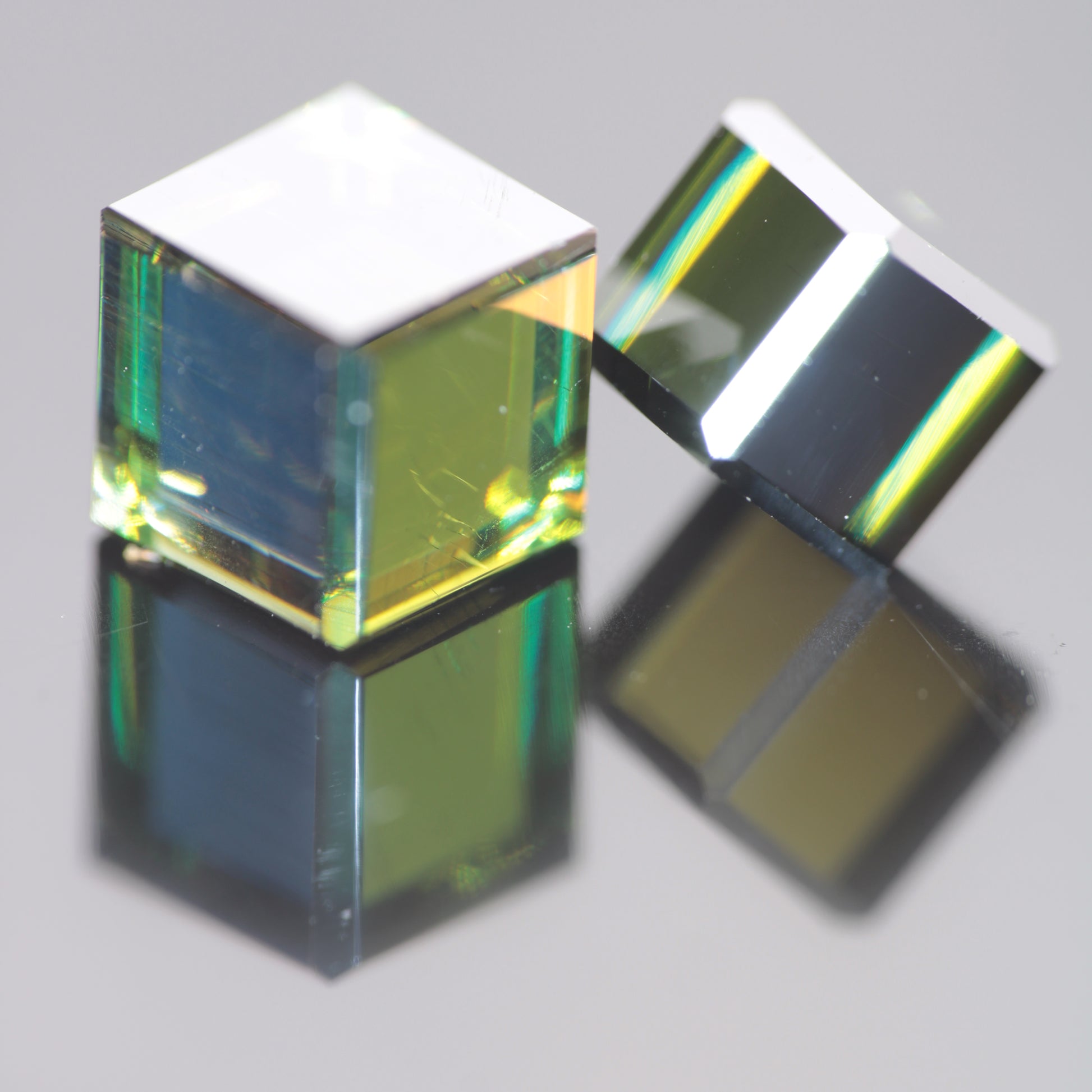 Two cubes of dichroic moissanite, the yellow and blue colors visible