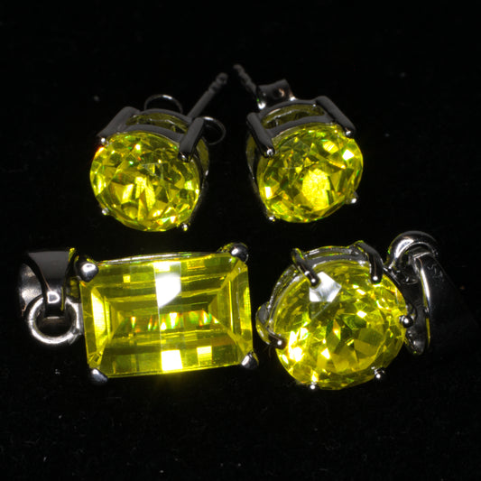 Bright yellow GAGG Jewelry, featuring a pair of sterling silver earrings at the top, a pixel pendant at bottom left and a round pendant at bottom right