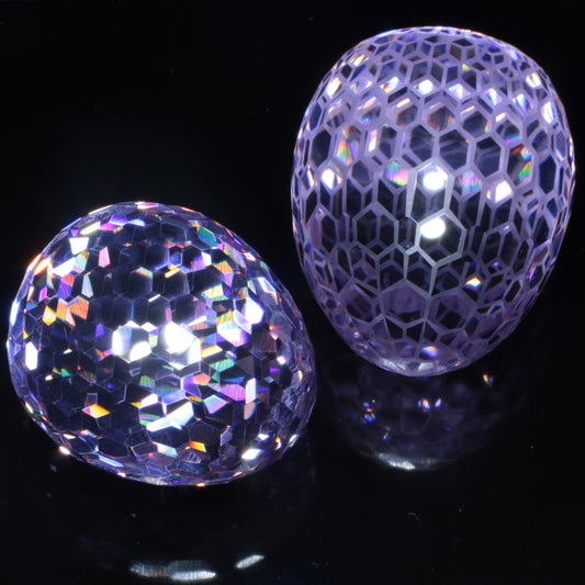 A pair of faceted purple Nd:YAG Eggs on a black background