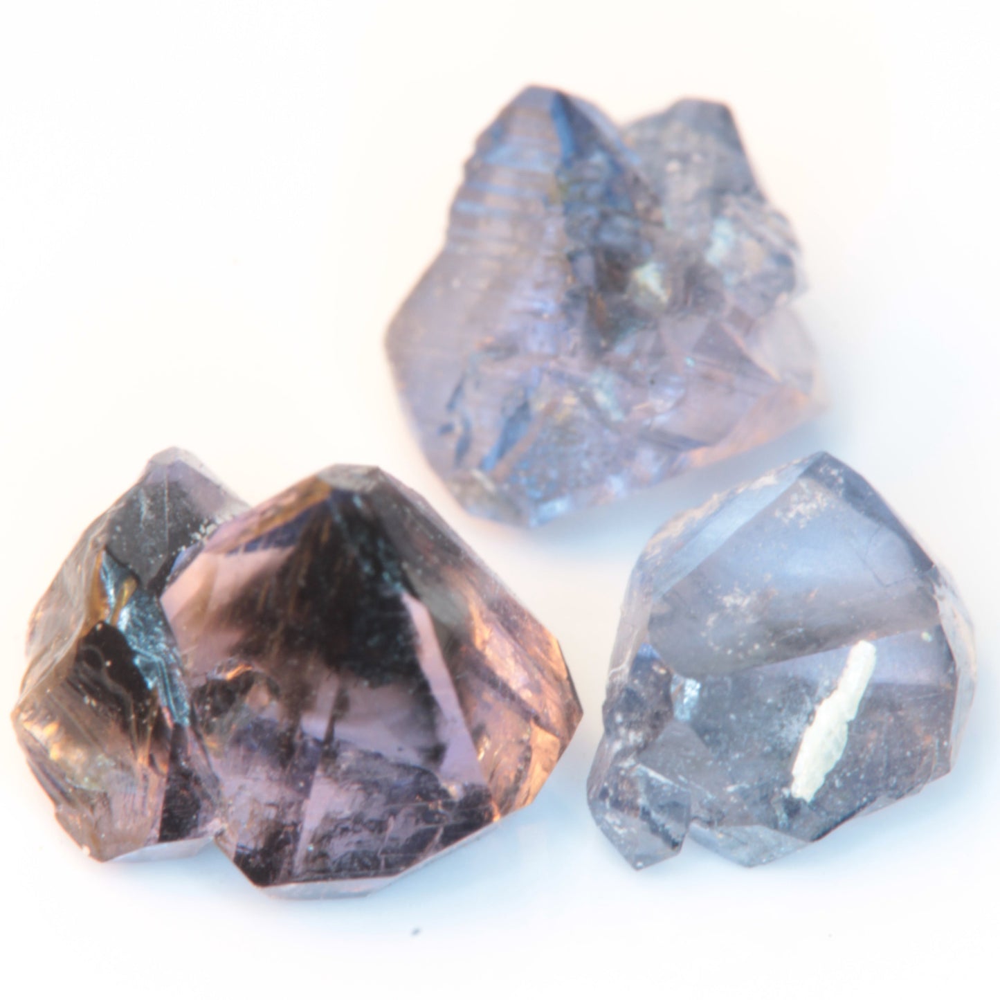Three flux-grown sapphires made by Gems of Science against a white background, showing the different forms and colors ranging from purple to blue.