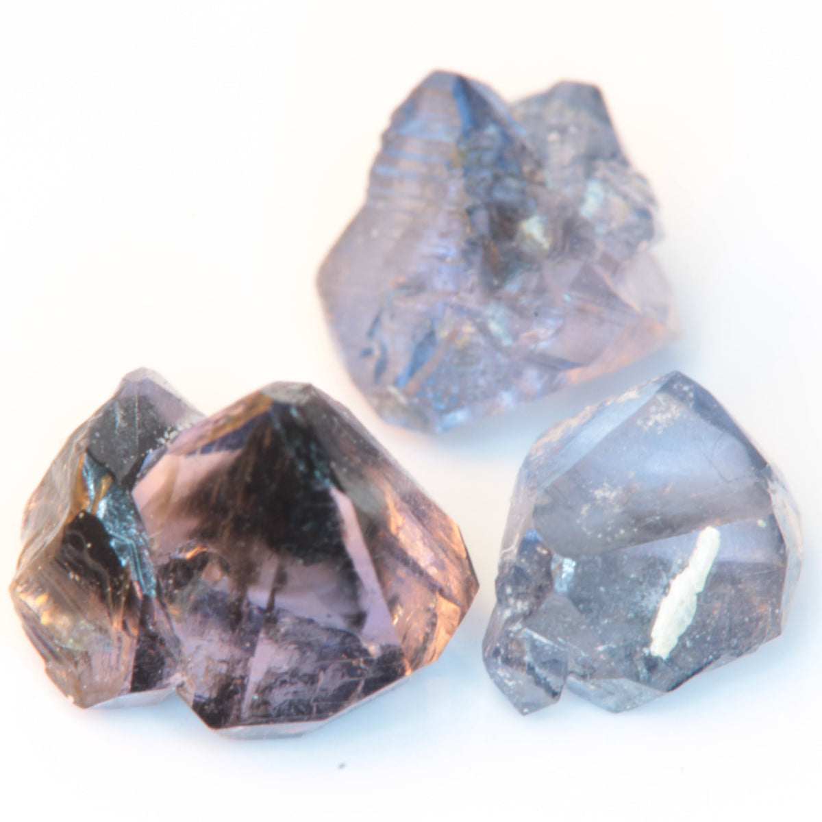 Three flux-grown sapphires made by Gems of Science against a white background, showing the different forms and colors ranging from purple to blue.