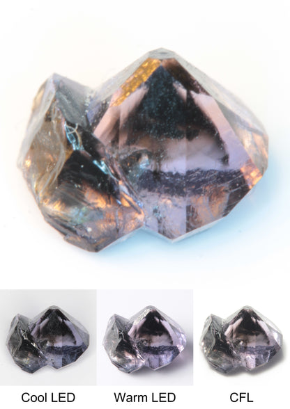 Synthetic Flux Playbutton Sapphire Gemstone Grown by Gems of Science on a white background showing color shift under different lighting