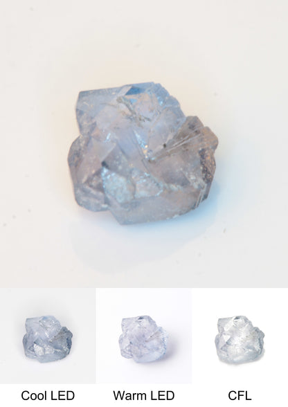 Synthetic Flux Playbutton Sapphire Gemstone Grown by Gems of Science on a white background showing color shift under different lighting