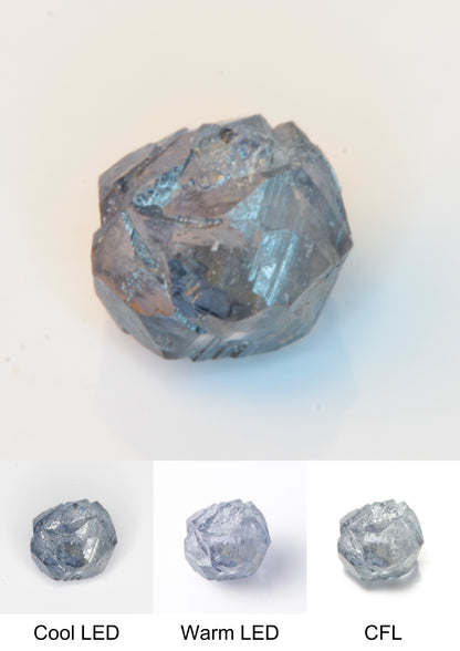 Synthetic Flux Playbutton Sapphire Gemstone Grown by Gems of Science on a white background showing color shift under different lighting