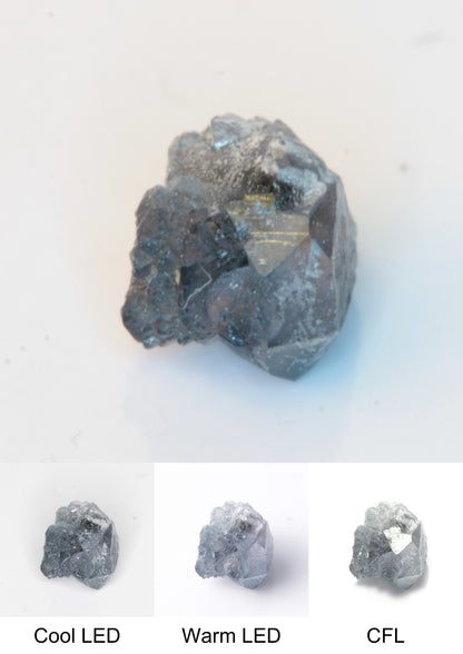 Synthetic Flux Playbutton Sapphire Gemstone Grown by Gems of Science on a white background showing color shift under different lighting