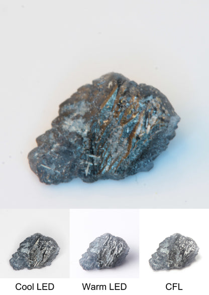 Synthetic Thin Flux Playbutton Sapphire Gemstone Grown by Gems of Science on a white background showing color shift under different lighting