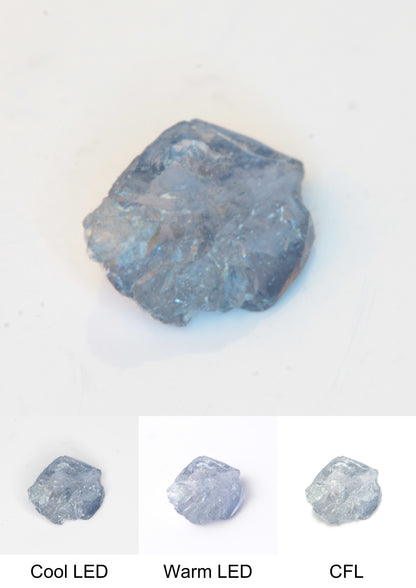 Synthetic Flux Playbutton Sapphire Gemstone Grown by Gems of Science on a white background showing color shift under different lighting