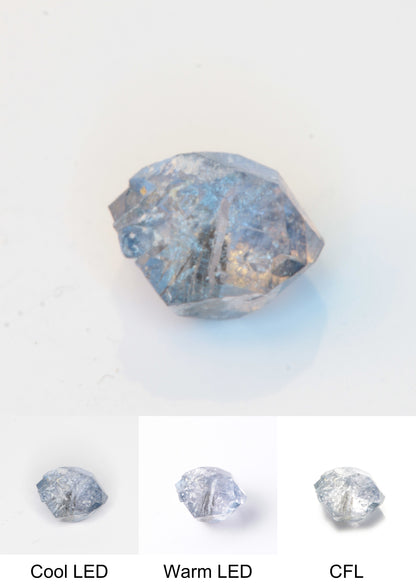 Synthetic Flux Playbutton Sapphire Gemstone Grown by Gems of Science on a white background showing color shift under different lighting