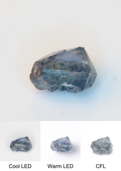 Synthetic Flux Playbutton Sapphire Gemstone Grown by Gems of Science on a white background showing color shift under different lighting
