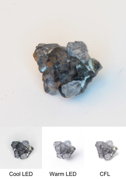 Synthetic Flux Playbutton Sapphire Gemstone Grown by Gems of Science on a white background showing color shift under different lighting