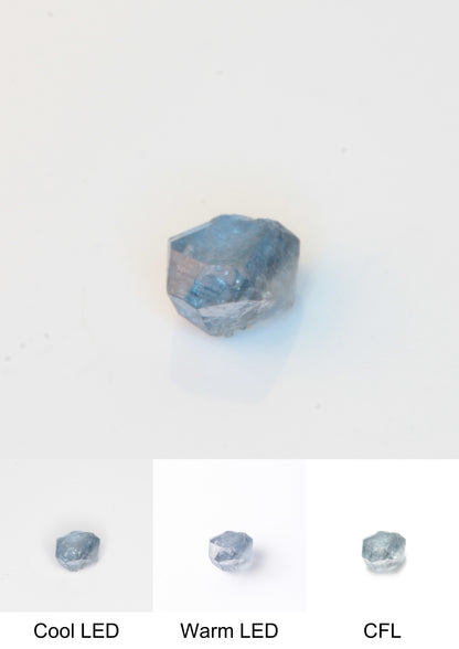 Synthetic Flux Playbutton Sapphire Gemstone Grown by Gems of Science on a white background showing color shift under different lighting
