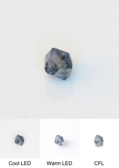 Synthetic Flux Playbutton Sapphire Gemstone Grown by Gems of Science on a white background showing color shift under different lighting
