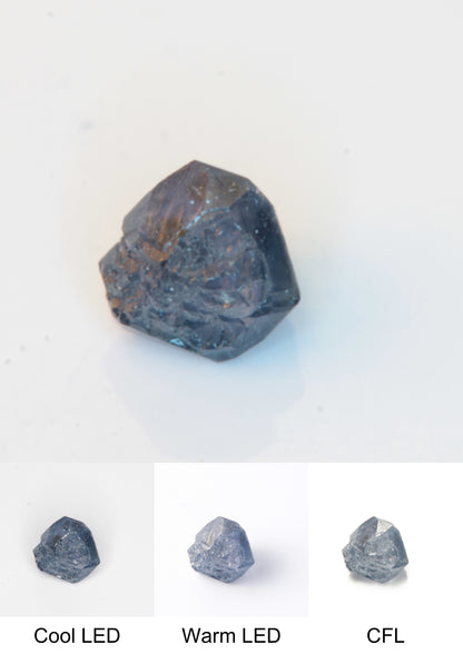 Synthetic Flux Playbutton Sapphire Gemstone Grown by Gems of Science on a white background showing color shift under different lighting