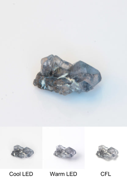 Synthetic Flux Playbutton Sapphire Gemstone Grown by Gems of Science on a white background showing color shift under different lighting
