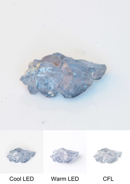 Synthetic Thin Flux Playbutton Sapphire Gemstone Grown by Gems of Science on a white background showing color shift under different lighting
