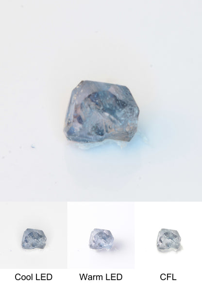 Synthetic Flux Playbutton Sapphire Crystal Gemstone Grown by Gems of Science on a white background showing color shift under different lighting