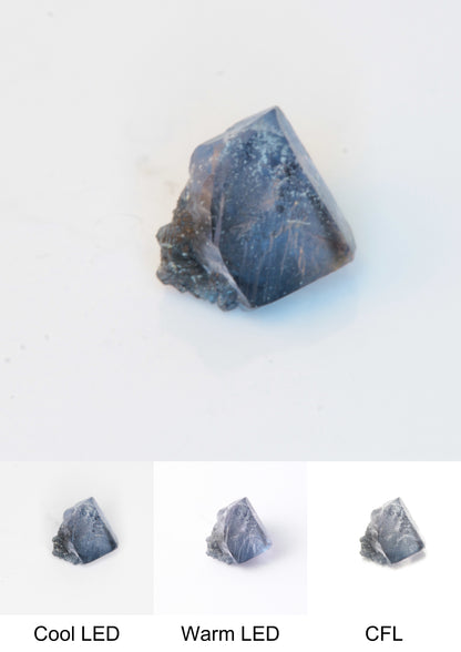 Synthetic Flux Playbutton Sapphire Gemstone Grown by Gems of Science on a white background showing color shift under different lighting