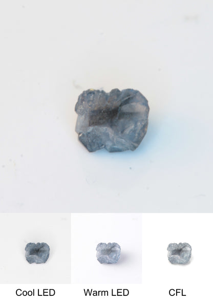 Synthetic Dark Core Flux Playbutton Sapphire Gemstone Grown by Gems of Science on a white background showing color shift under different lighting