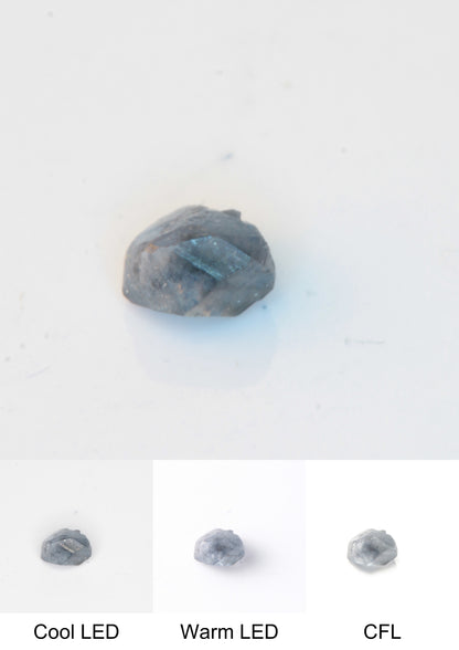 Synthetic Flux Playbutton Sapphire Gemstone Grown by Gems of Science on a white background showing color shift under different lighting