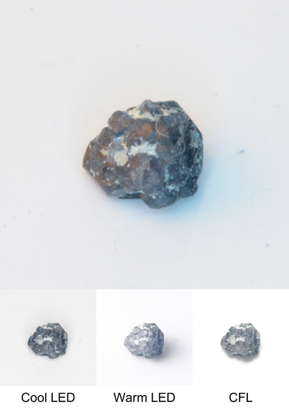 Synthetic Flux Playbutton Sapphire Gemstone Grown by Gems of Science on a white background showing color shift under different lighting