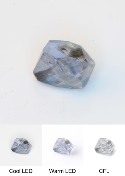Synthetic Flux Playbutton Sapphire Gemstone Grown by Gems of Science on a white background showing color shift under different lighting