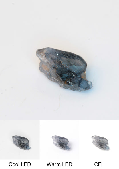 Synthetic Flux Playbutton Sapphire Gemstone Grown by Gems of Science on a white background showing color shift under different lighting