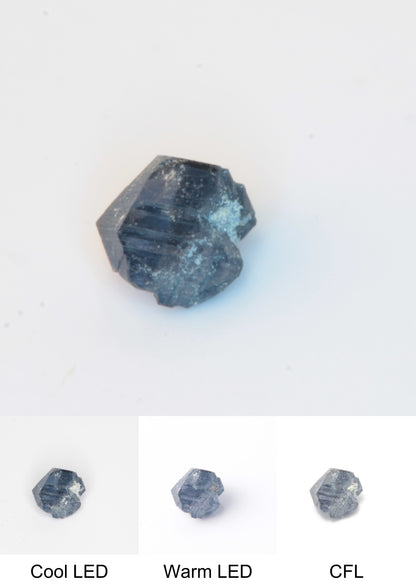 Synthetic Flux Playbutton Sapphire Gemstone Grown by Gems of Science on a white background showing color shift under different lighting