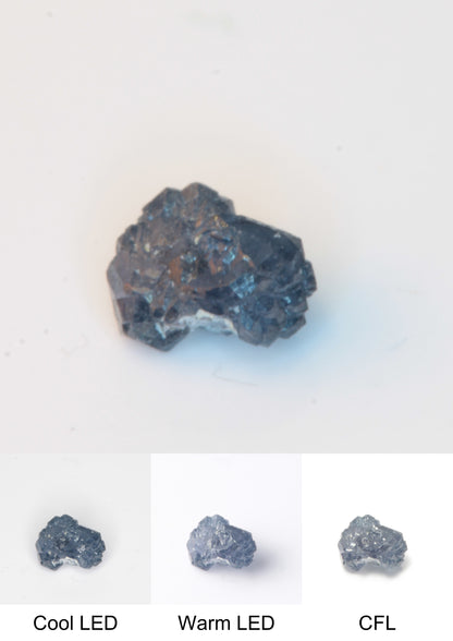 Synthetic Flux Playbutton Sapphire Gemstone Grown by Gems of Science on a white background showing color shift under different lighting