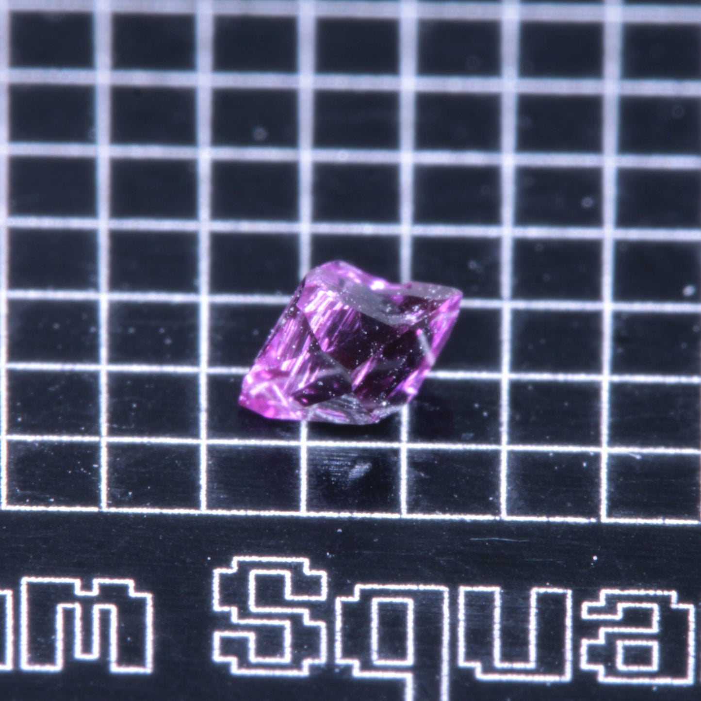 A synthetic ruby crystal on a black grid background