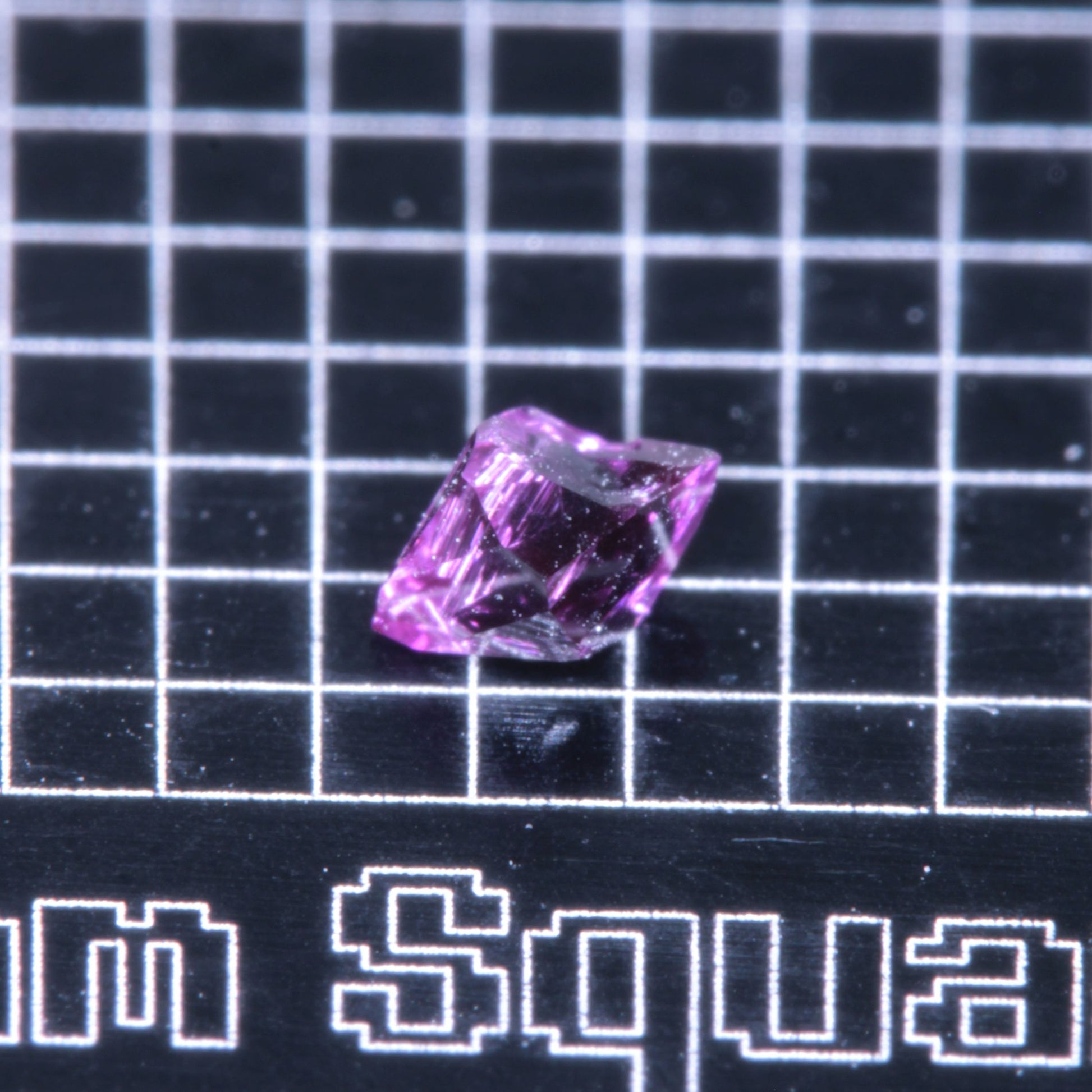 A synthetic ruby crystal on a black grid background