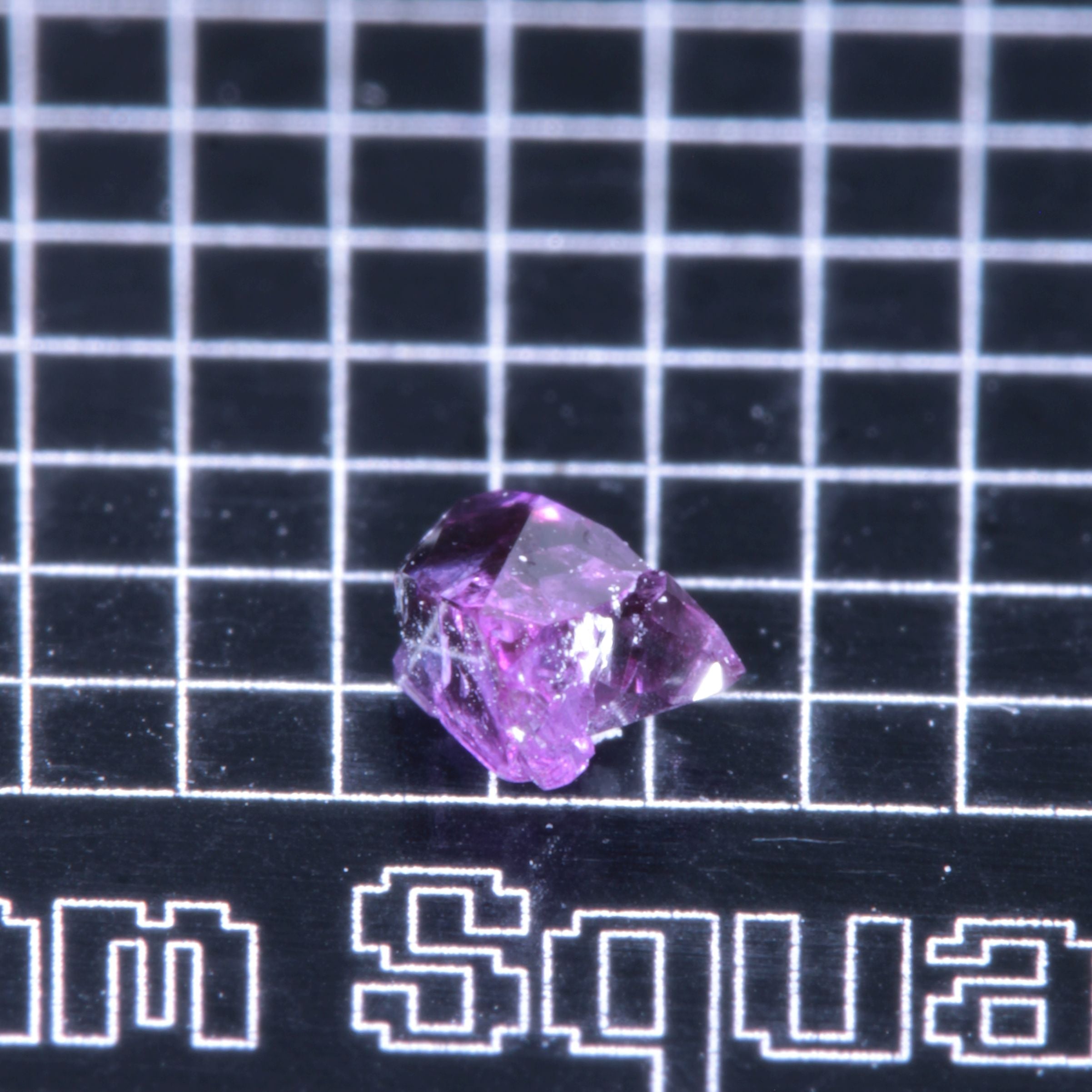 A synthetic ruby crystal on a black grid background