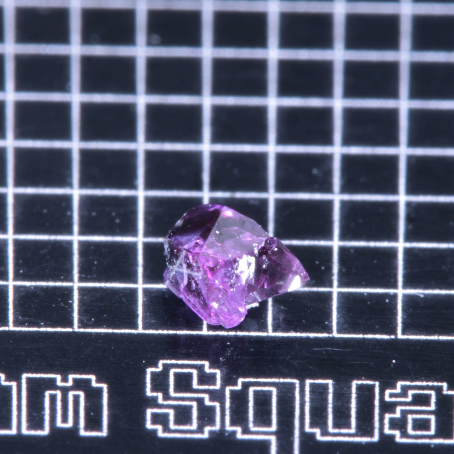 A synthetic ruby crystal on a black grid background