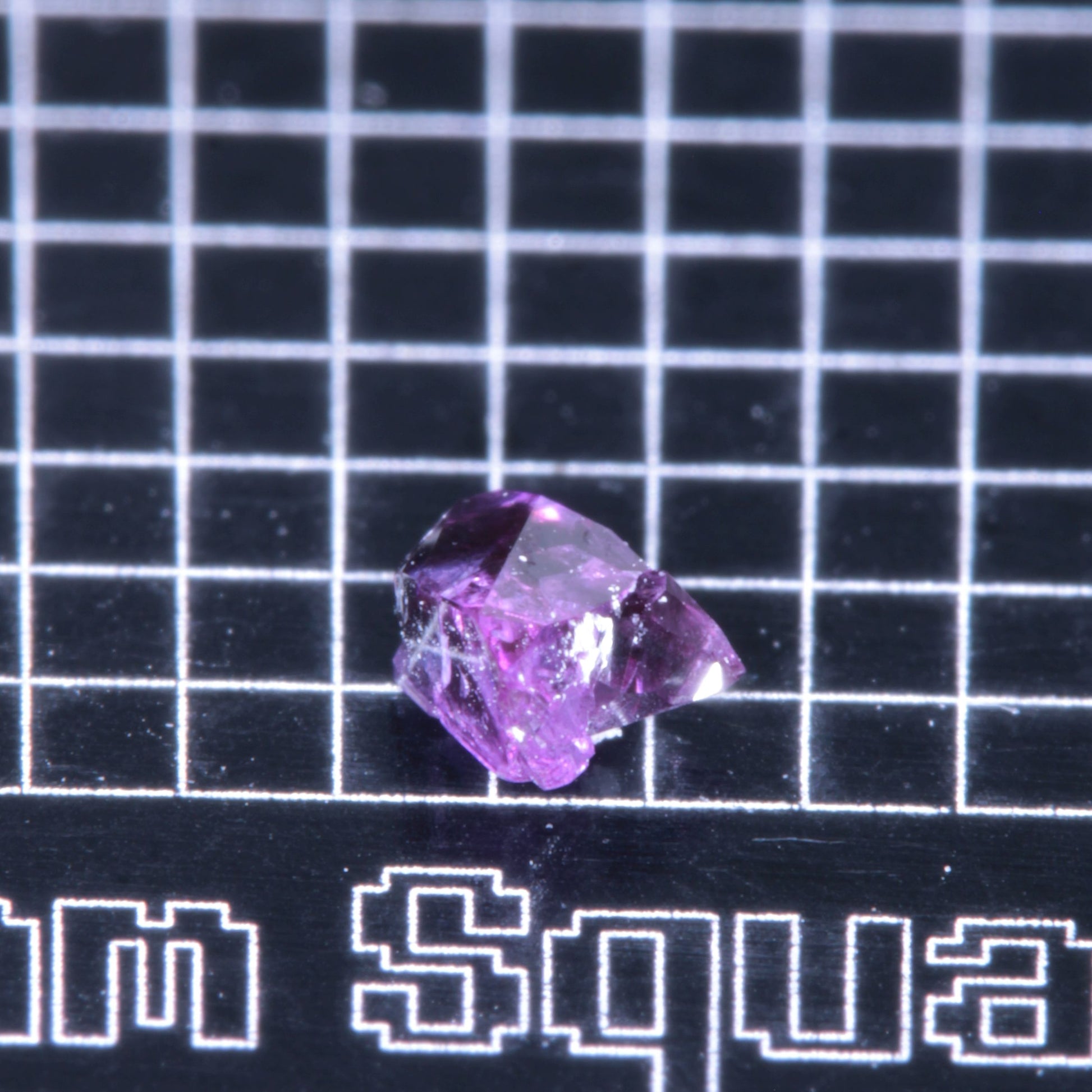 A synthetic ruby crystal on a black grid background