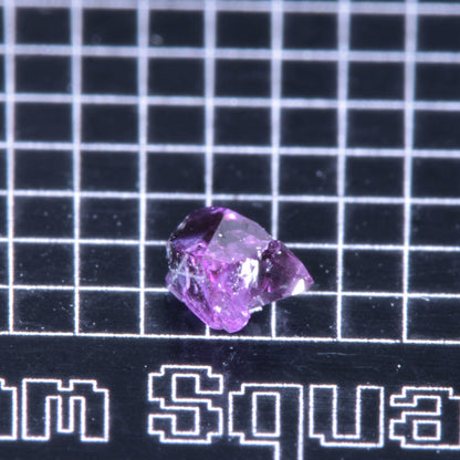 A synthetic ruby crystal on a black grid background