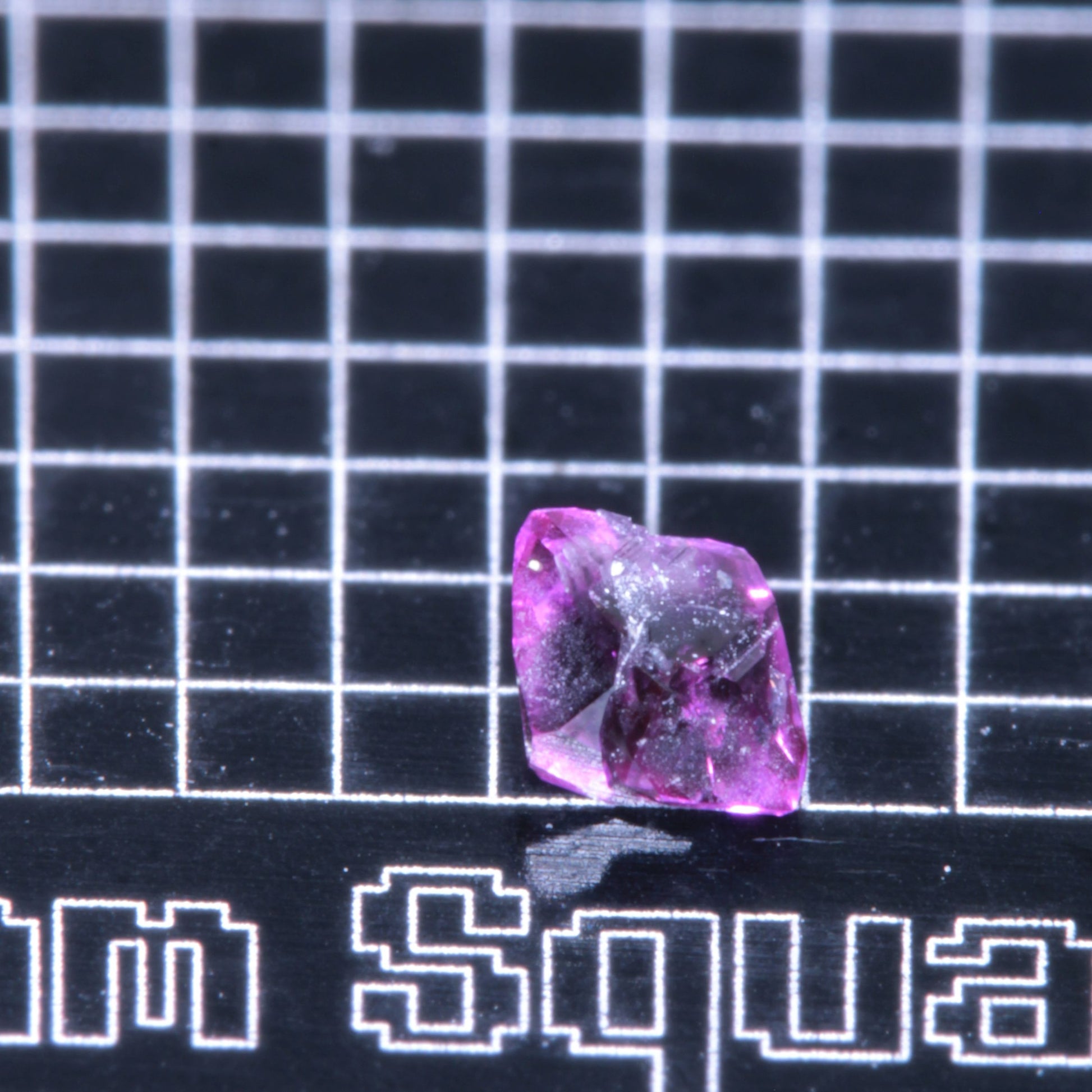 A synthetic ruby crystal on a black grid background