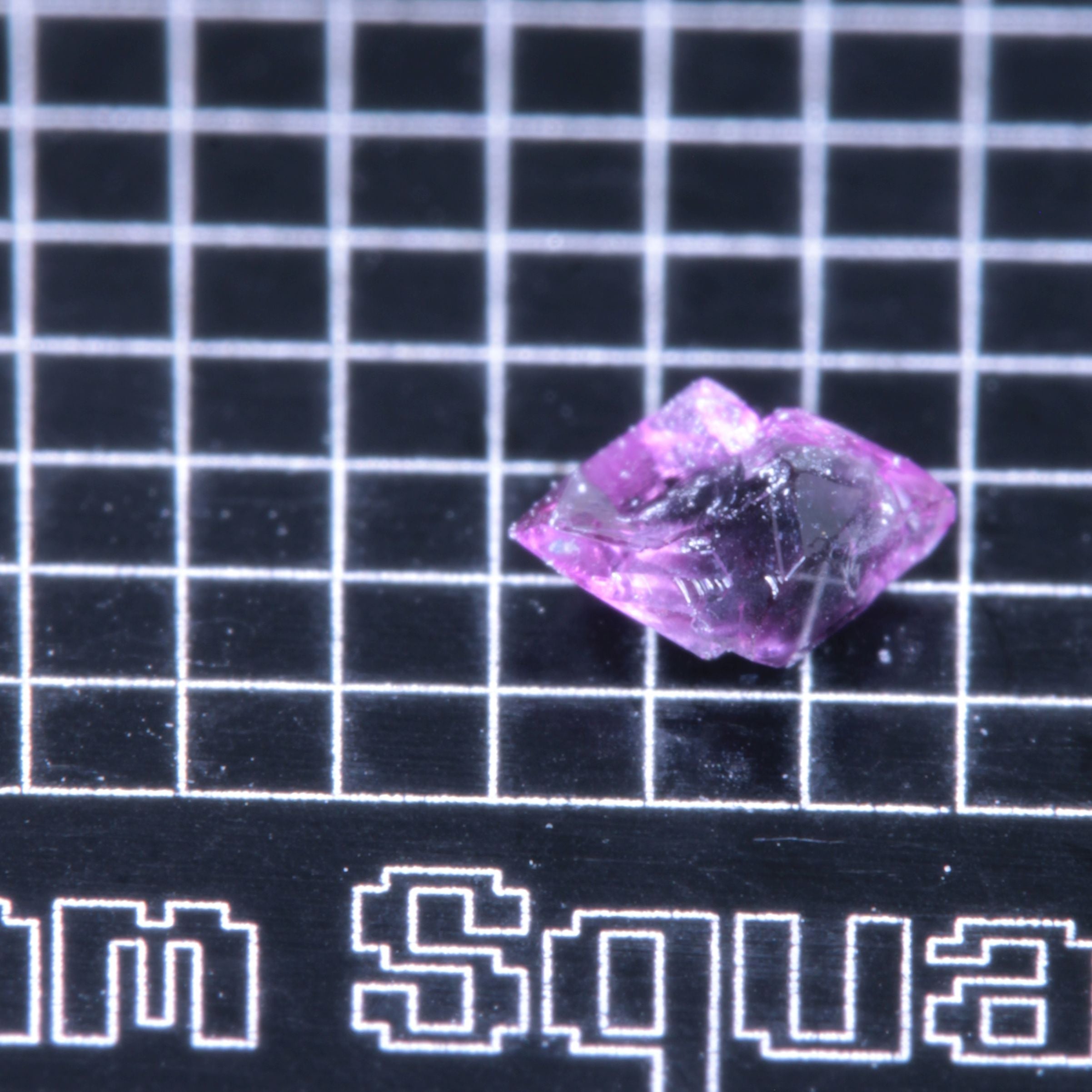 A synthetic ruby crystal on a black grid background