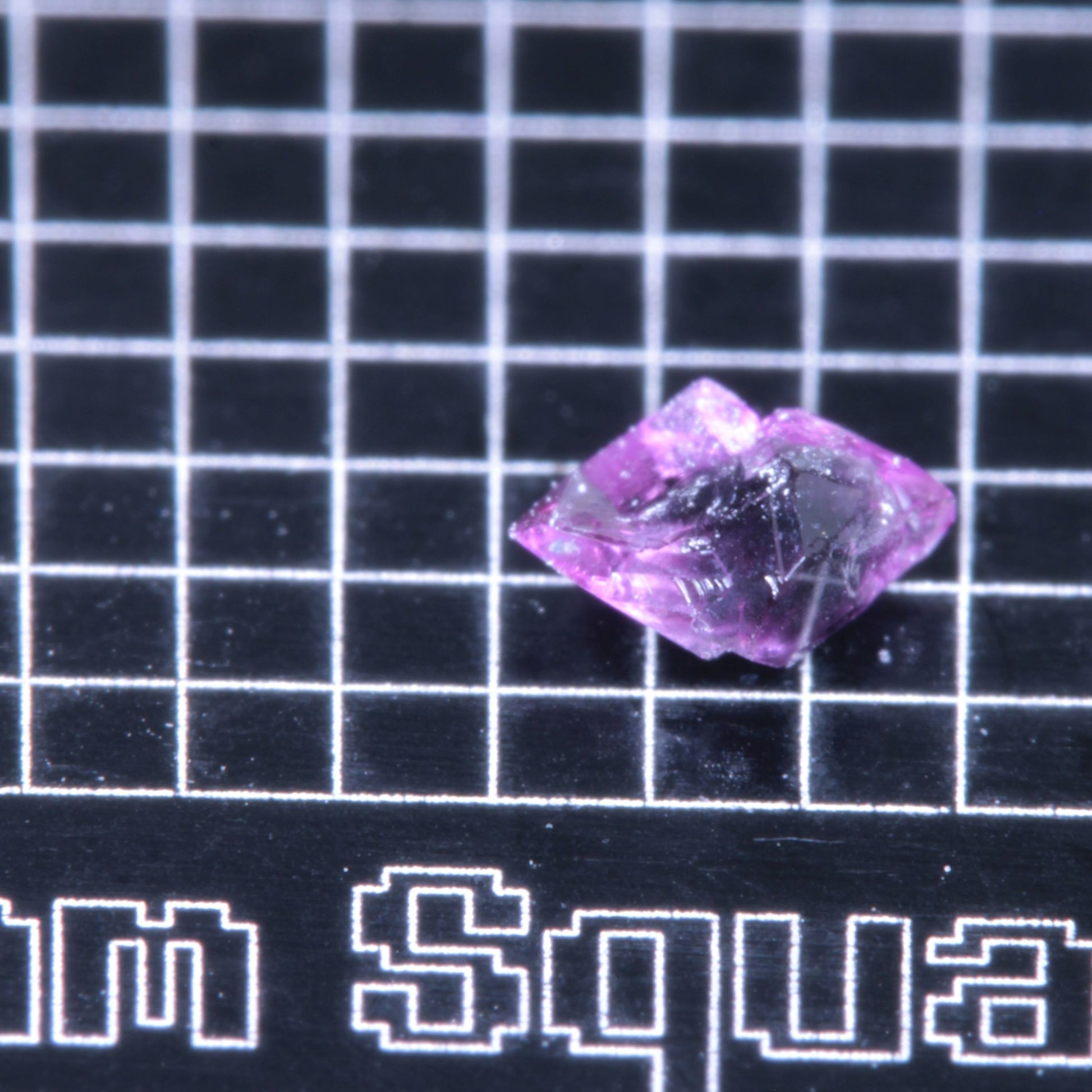 A synthetic ruby crystal on a black grid background