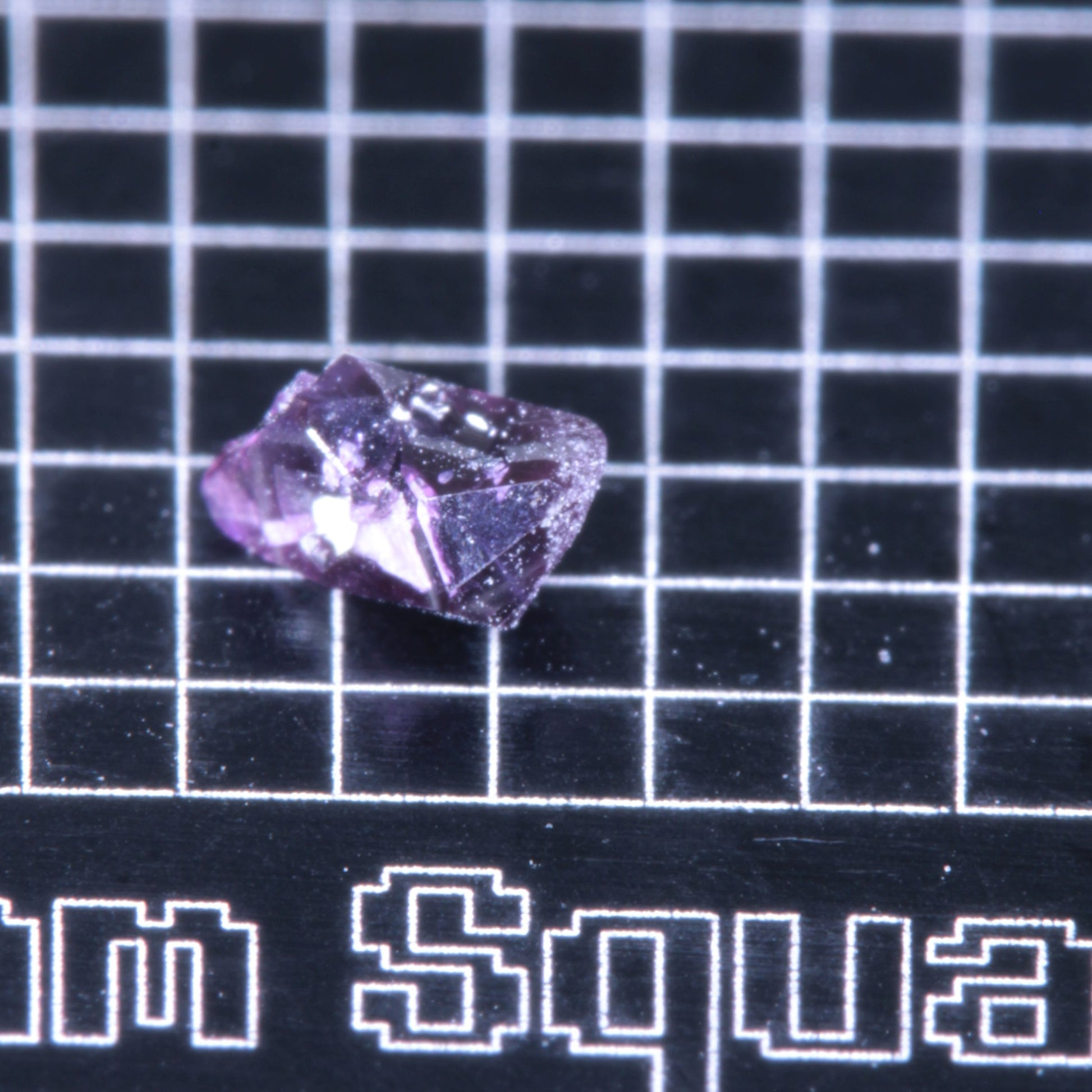 A synthetic ruby crystal on a black grid background