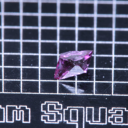 A synthetic ruby crystal on a black grid background