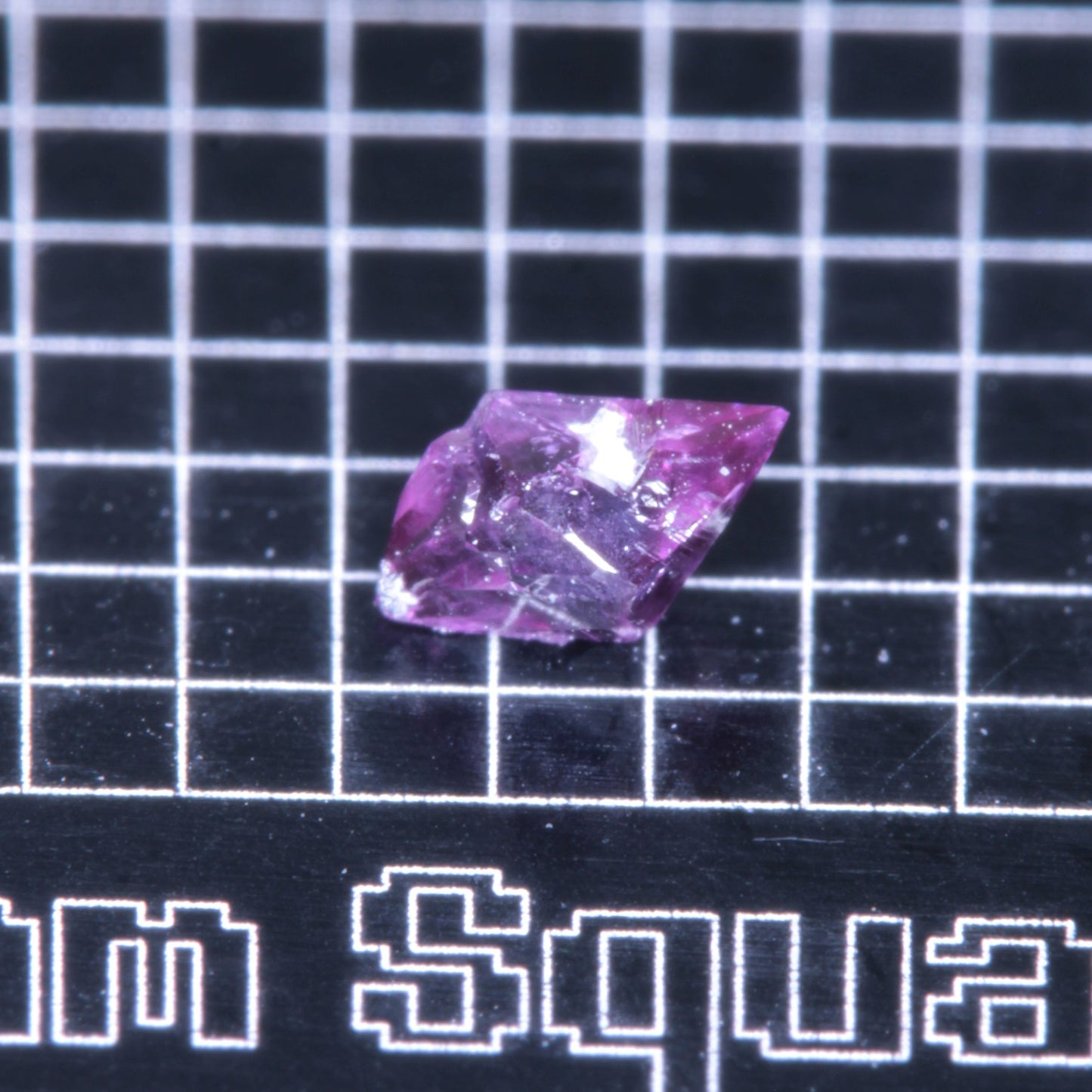 A synthetic ruby crystal on a black grid background