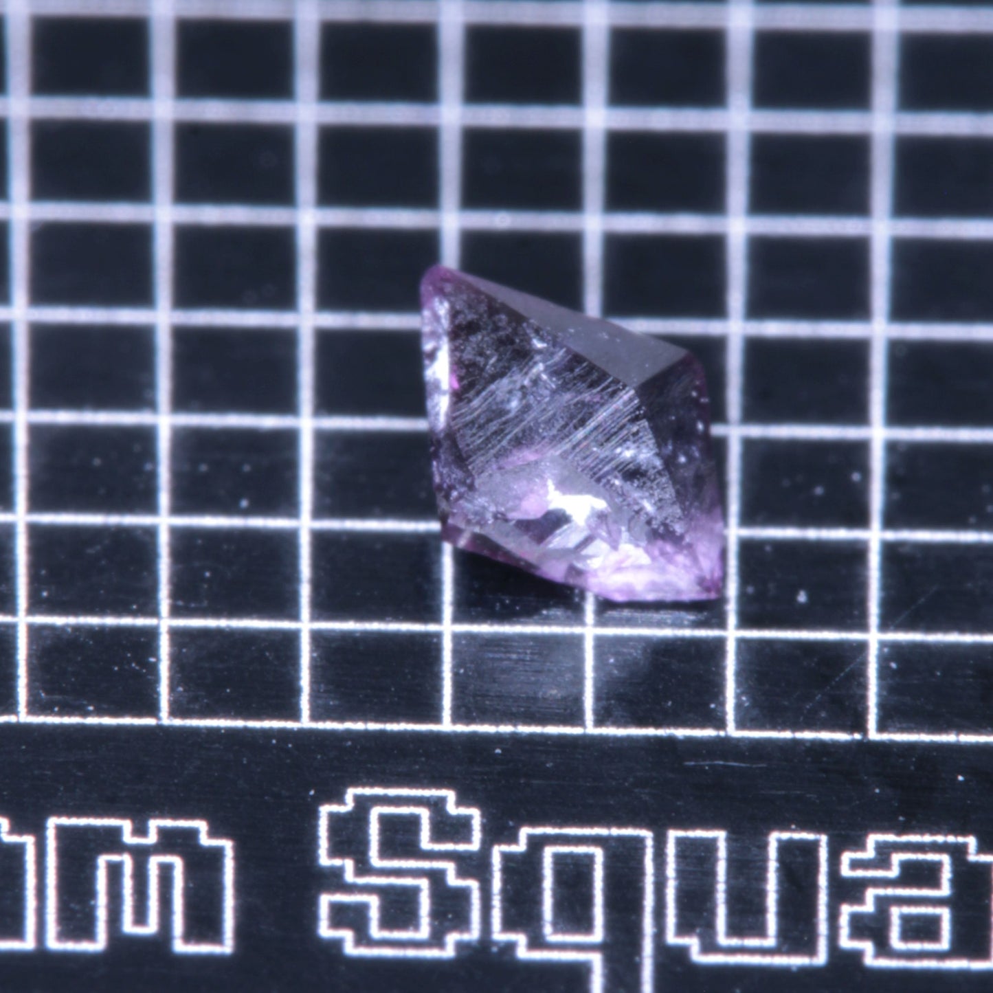 A synthetic ruby crystal on a black grid background
