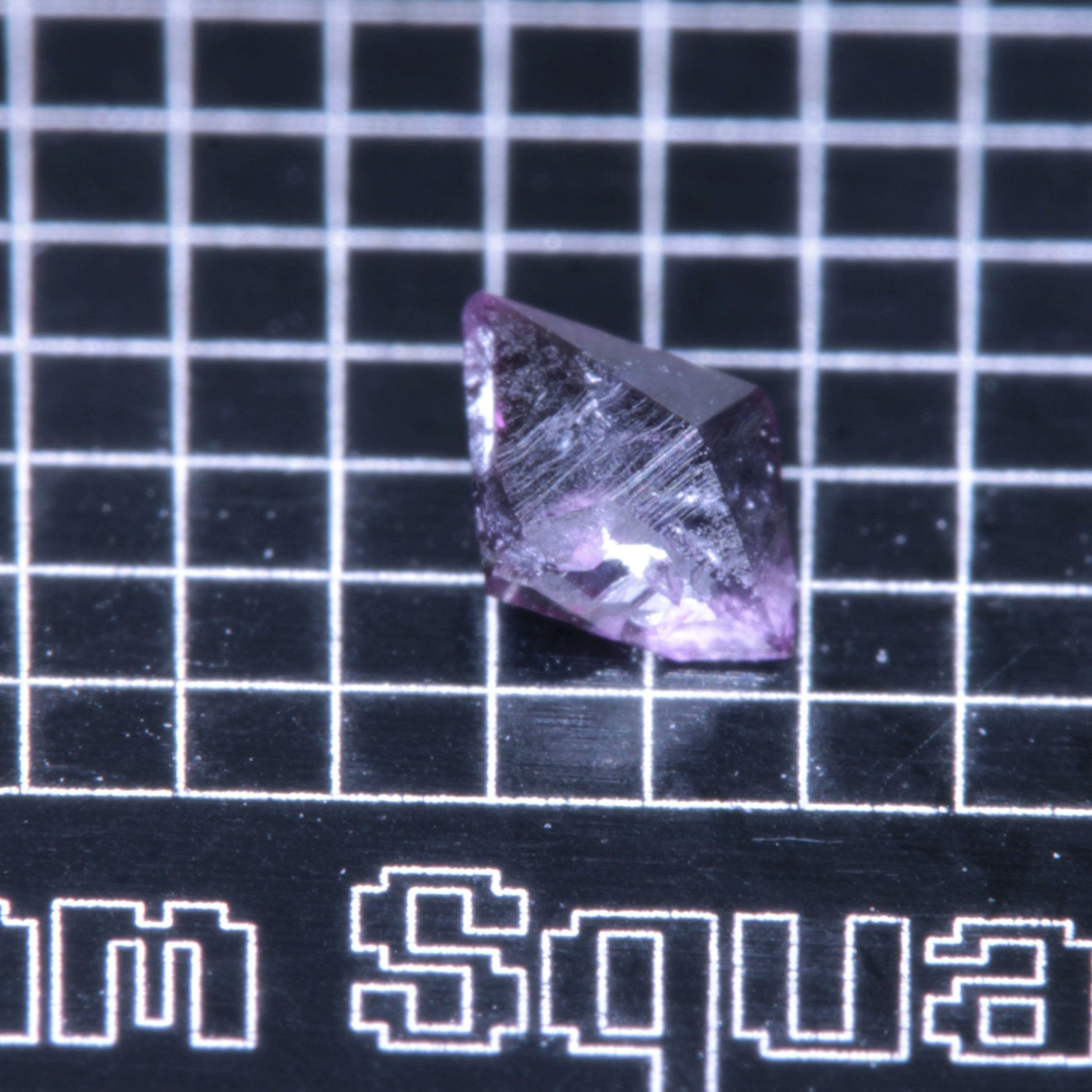 A synthetic ruby crystal on a black grid background